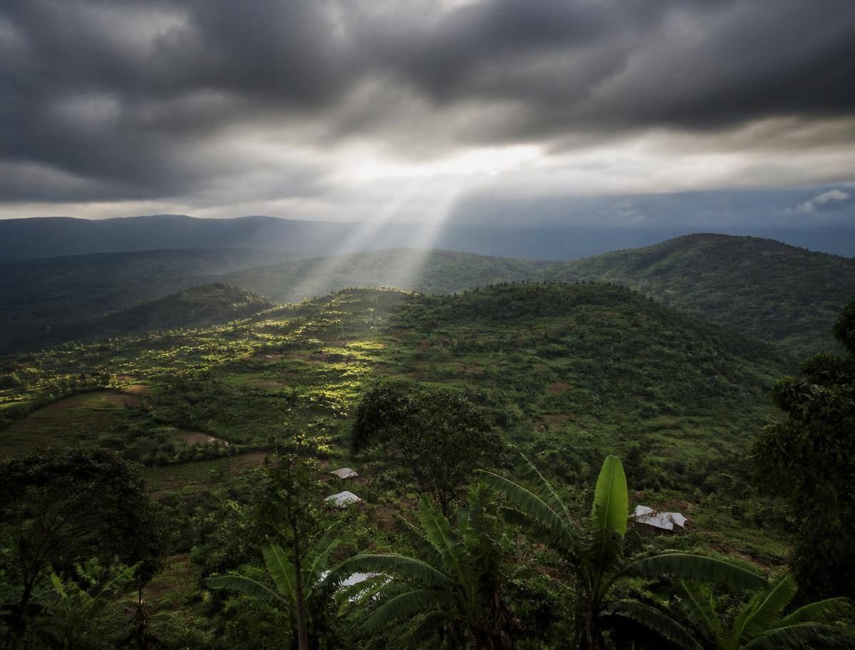Nuages de pluie et rayons de soleil au-dessus des collines cultivées du Burundi